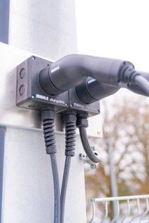 Modern electric charging station with cable connections on metal, parking garage construction with