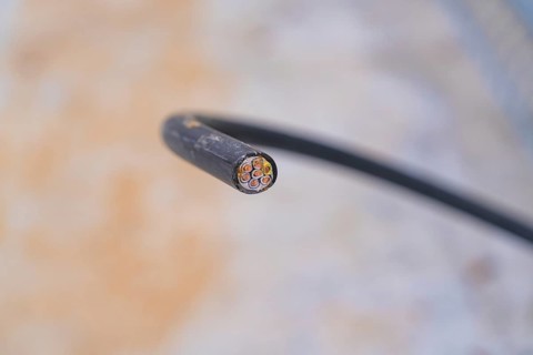 Close-up of a cut cable with visible wires, parking garage construction with charging