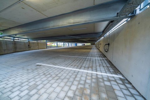 Empty covered parking lot with concrete structure and marked parking spaces, parking garage