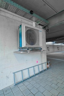 Air conditioning system placed on a concrete wall and a ladder in a parking garage, parking garage