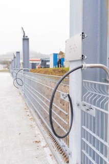 Electrical cable in front of a grey fence in an industrial area, parking garage construction with
