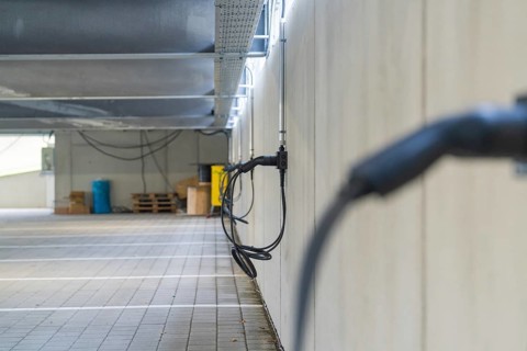 Electric charging cable on car park wall with concrete look, parking garage construction with