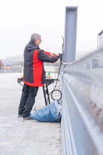 Man working on electrical cable installation in open area, parking garage construction with