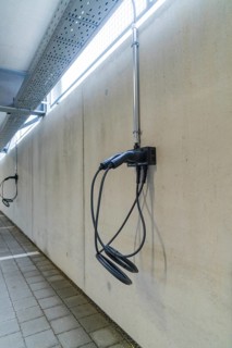 Electric charging station mounted on a concrete wall in a parking garage, parking garage