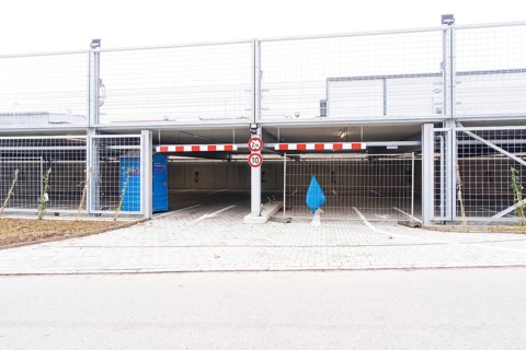 An empty parking deck with a barrier and a traffic sign. The area is secured by fences, car park