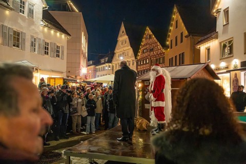 Santa Claus standing on stage in front of a crowd at night, Weihnachtsmark Nagold, LandkreiScalw,