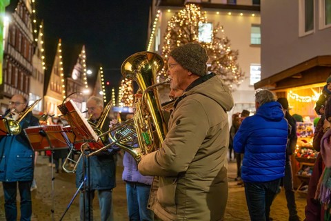 Brass players play at a Christmas market with festive lighting, Weihnachtsmark Nagold,