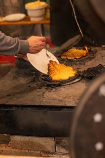 A person picks waffles baked fresh at a market from an oven, Weihnachtsmark Nagold, LandkreiScalw,