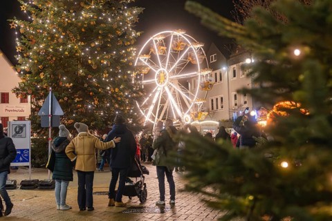 People enjoy the Christmas atmosphere with tree and Ferris wheel at night, Weihnachtsmark Nagold,