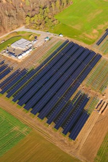 Aerial view of a large solar plant surrounded by autumn trees and fields, energy revolution,