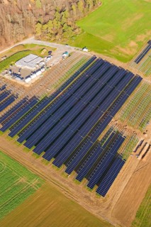 Large solar park right on the edge of an autumn forest and green fields, energy revolution,
