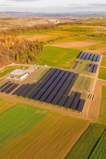 Solar systems in fields surrounded by autumn trees and a village, Energiewende, construction of PV