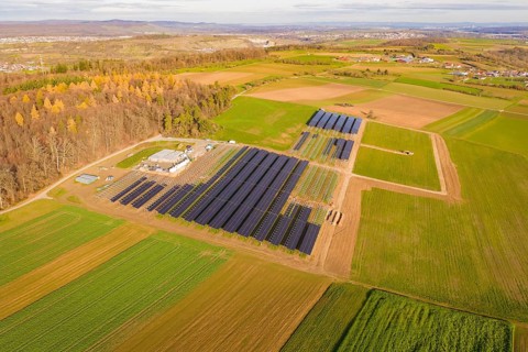 Large solar plant surrounded by autumnal fields and a village in the background, Energiewende,