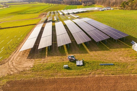 Aerial view of a solar installation site surrounded by green fields, energy revolution,