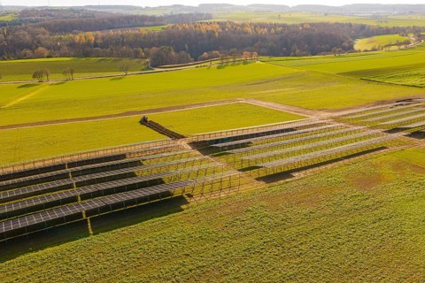 Incomplete solar panel structures on a green area in a vast landscape, energy revolution,