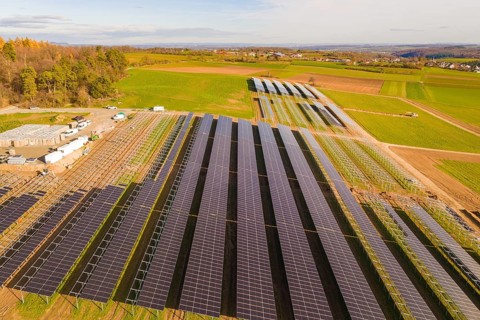 Large solar field surrounded by green fields and hills, sunny atmosphere, energy revolution,