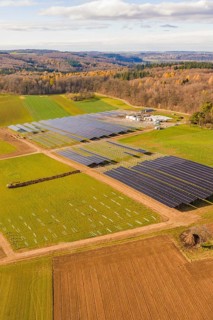 Aerial view of a solar park surrounded by fields and autumn forests, energy revolution,