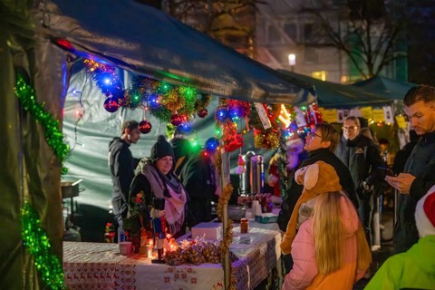 Colourful and festively decorated stands at a Christmas market with many visitors, Christmas