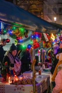 Christmas market with decorated stands and glowing lights, surrounded by people in a festive mood,