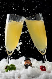 Two sparkling champagne glasses in the snow with lucky New Year's Day charms