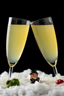Two champagne glasses in the snow surrounded by lucky New Year's Day charms