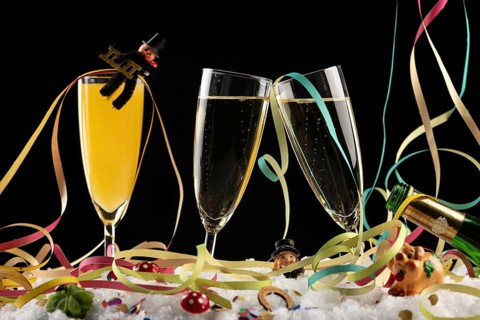 Three champagne glasses with lucky charms for the New Year and streamers in the snow
