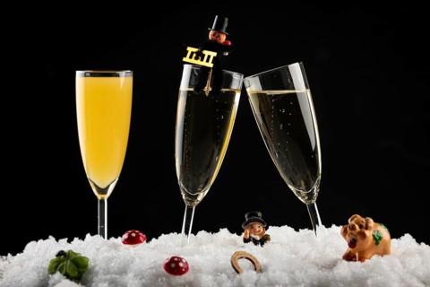 Three champagne glasses with lucky charms for New Year in the snow