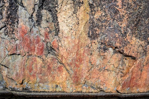 Prehistoric rock art in reddish brown on a textured surface Rock paintings of Värikallio, rock wall