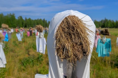 Artwork outdoor installation The silent people of Reijo Kela Straw dolls wear colorful clothes in a