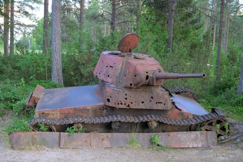 Rusted tank in the forest with visible signs of age and vegetation, museum at the Winter War