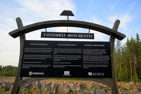 Black memorial plaque for the Winter War Memorial in front of a rocky field and forest, Kotiranta,