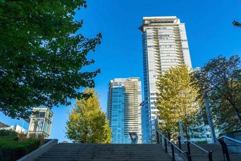 Modern skyscrapers rise above green trees in vancouver, british columbia, on a clear sunny day,