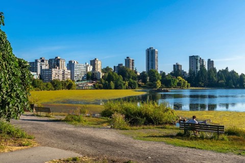 Vancouver city skyline reflecting on trout lake with yellow algae bloom during summer in british