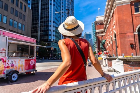 Young woman wearing a straw hat and an orange dress is enjoying the urban landscape of vancouver.