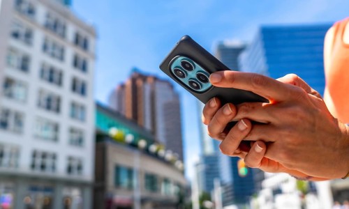 Close up of hands holding smartphone with multiple camera lenses, using navigation app in vancouver