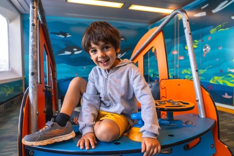 Happy child smiling and playing on a colorful play structure aboard a ferry traveling from victoria