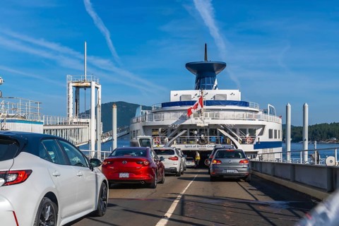 Cars are boarding a ferry with a canadian flag, departing from victoria on vancouver island to