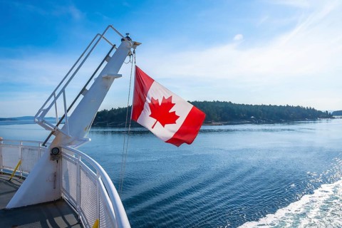 The canadian flag waves proudly from a ferry traveling between victoria on vancouver island and