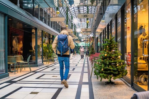 Person walking through a festively decorated shopping center with glass roof, Calwer Passage,