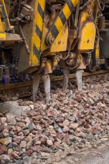 Detailed view of a gravel and track construction machine with yellow-black painting, stuffing