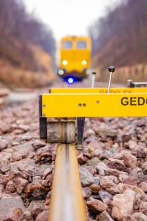 Close-up of a rail surveyor, a yellow vehicle in the background, tamping machine on the Hermann,