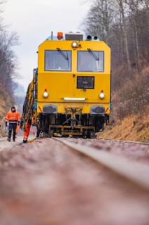 Yellow track construction equipment on rail road, worker watching work, stuffing machine on