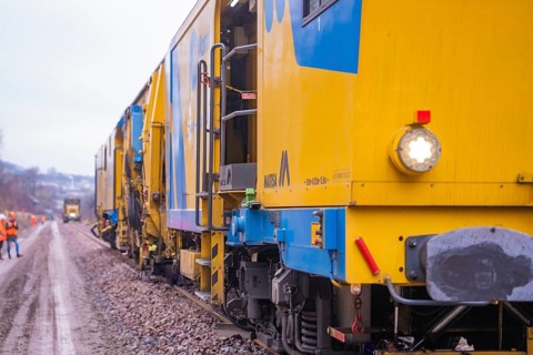 Several yellow work trains run along a rail route to maintenance, tamping machine on Hermann,