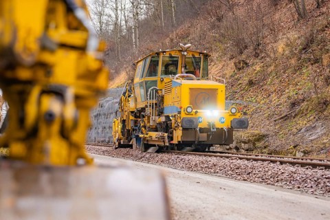 Rail construction machine in use on railroad tracks, indicated blur in the foreground, stuffing
