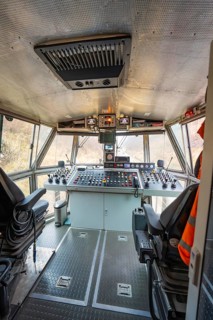 Spacious train driver's cab with comprehensive control panel and seating, stuffing machine on