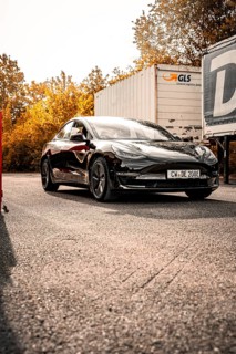 Black car on a road in a sunny autumn landscape, Deer e-Carsharing, Tesla Model 3, Calw, Germany