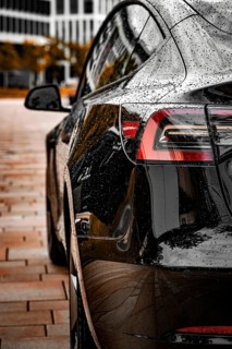 Close-up of a black vehicle with a rain-wet surface in an urban environment, Deer E-Carsharing,