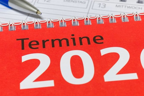 Close-up of a red calendar for 2026 with spiral binding and blue pen, diary