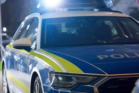 Symbolic image of a police operation: police emergency vehicle with flashing blue lights (digitally