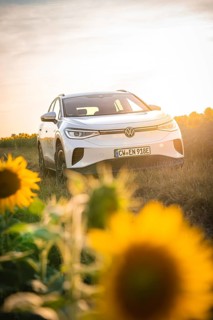 A white car is standing leaning against sunflowers at sunset, VW ID4 electric car, Deer Carsharing,